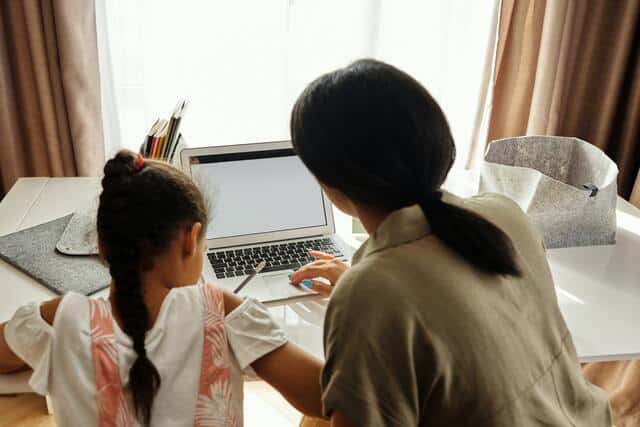 Estrategias para estudiar a distancia. Madre estudiando junto a su hija pequeña mientras ella dibuja.